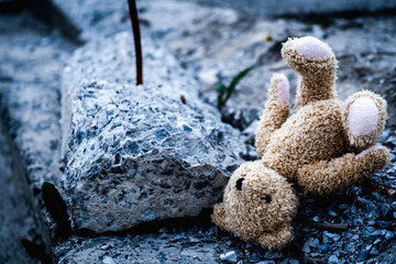 Russia's war against Ukraine, ruined children's lives as a result of Russian aggression, loss childhood and future.  Children's toy teddy bear against the concrete background of destroyed building.