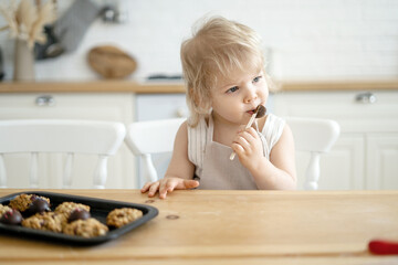 Happy childhood little girl in the apartment playing eating sweets