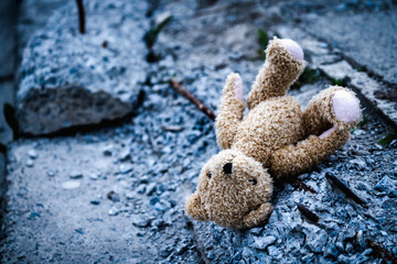 Conceptual image: loss childhood and future.  Children's toy teddy bear lies on broken construction...