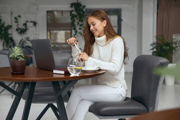 Young woman working on laptop while sitting in cafe