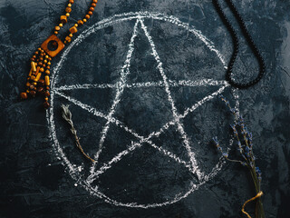 Top view of a painted pentagram for a ritual and an ancient amulet