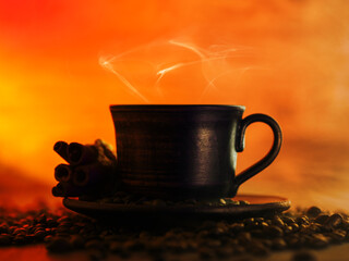 A cup of hot coffee silhouette on the table with coffee beans. Orange background