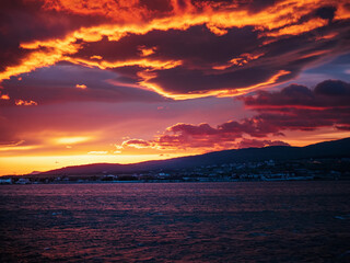 Fototapeta premium Sunset sky with red orange and violet clouds over sea.