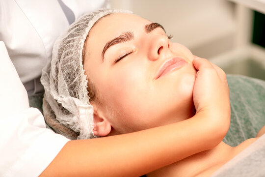 Facial massage. Hands of a masseur massaging neck of a young caucasian woman in a spa salon, the concept of health massage