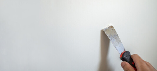 Man repairing crack white wall with spatula