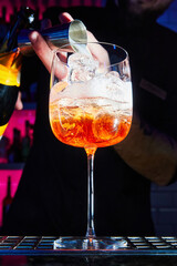 Bartender prepares Aperol Spritz cocktail on bar counter. Close-up, selective focus