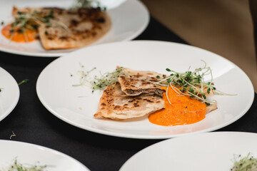 Cheburek traditional balkan meat pastry pie with herbs on a white plate. Served with sauce and micro green