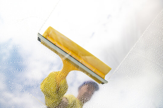 window cleaner cleaning window with squeegee and wipe