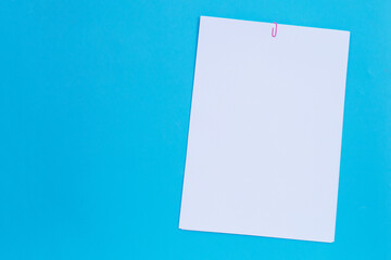 white paper with clip on blue background.