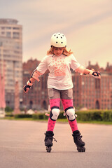 A child of ten is rollerblading in the park. The girl is wearing fall protection. Roller skating...