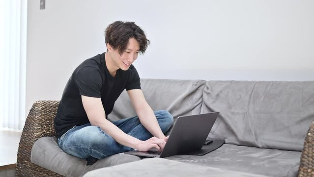 チャットをしながらパソコンの仕事をするハンサムな男性
