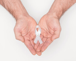White awareness ribbon. Lung cancer awareness white ribbon bow on man hands. Anti violence against...