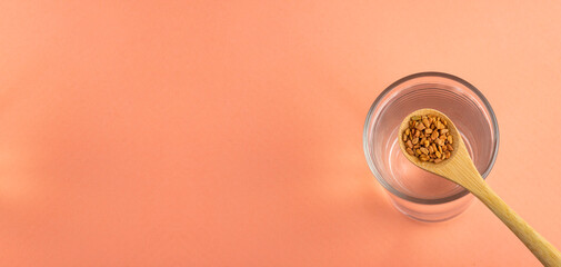 Spoon with fenugreek seeds and glass of filtered water