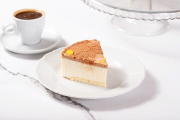 A piece of dessert on a white plate on a white marble table