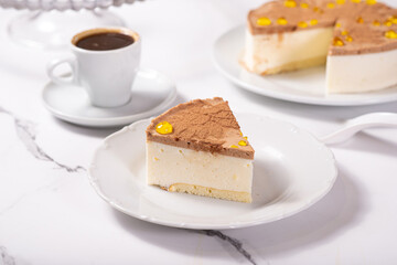 A piece of dessert on a white plate on a white marble table