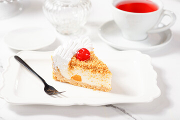 A piece of dessert on a white plate on a white marble table