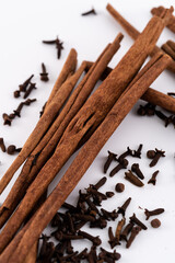 Cinnamon sticks and dried cloves on a white background.