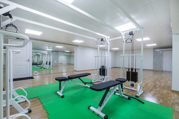 Fototapeta na wymiar A bright gym room with large mirrors and exercise equipment on green mats.