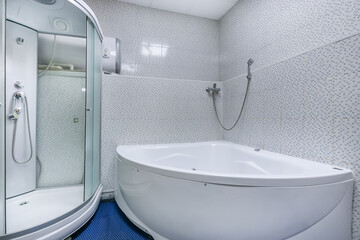 A bright bathroom with a spacious shower cabin and a bathtub in the SPA or fitness center.