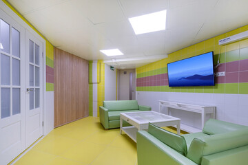 A recreation room in the wellness center with an entrance door, decorated in pastel colors.