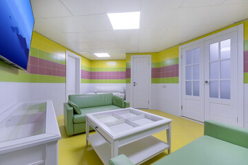 A relaxation area in the wellness center in pastel colors with a TV and sofas.