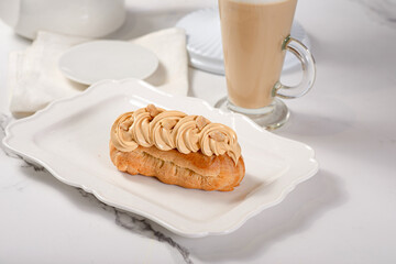 Fresh dessert on a white plate among white dishes with tea and coffee in a cafe