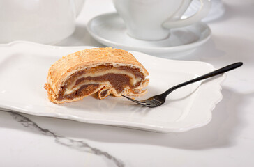 Fresh pastries on a white plate on a marble white table among white dishes with coffee and tea