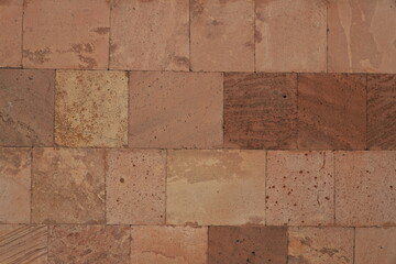 A fragment of a wall made of bricks made of natural stone - pink tuff.