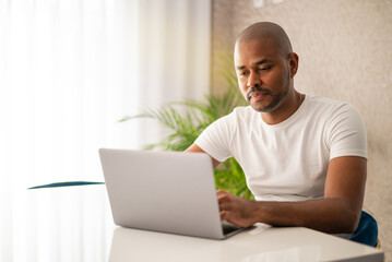 Young man at home messaging online on laptop