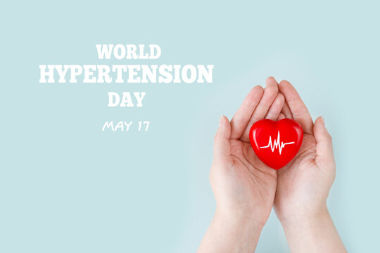 World Hypertension Day. Women's hands hold a red heart with a heartbeat chart with his hands - a symbol of high blood pressure. Hypertension Day in May 17th. World heart day, world health day.