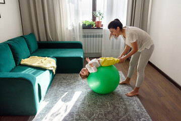 Mother do exercises playing with her baby at home.