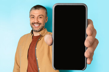Middle Aged Man Showing Huge Phone Empty Screen, Blue Background