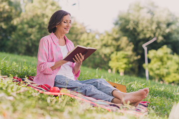 Photo of cute charming lady pensioner wear pink shirt sitting blanket reading interesting story outdoors countryside garden