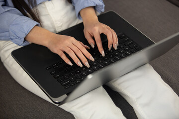 Young programmer girl coding on laptop. Freelancer woman typing text on modern notebook computer at home