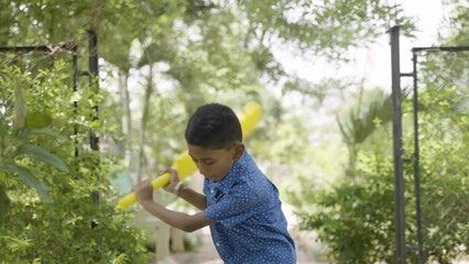 tracking shot of young teenager kid with bat coming to play cricket at park by making actions - concept of aspirations