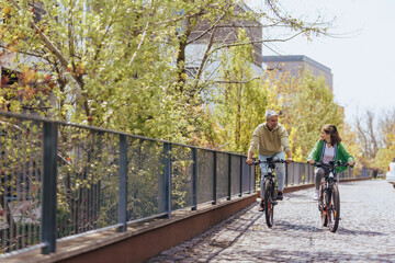Happy father with teenage daughter on cycle ride in town. - obrazy, fototapety, plakaty