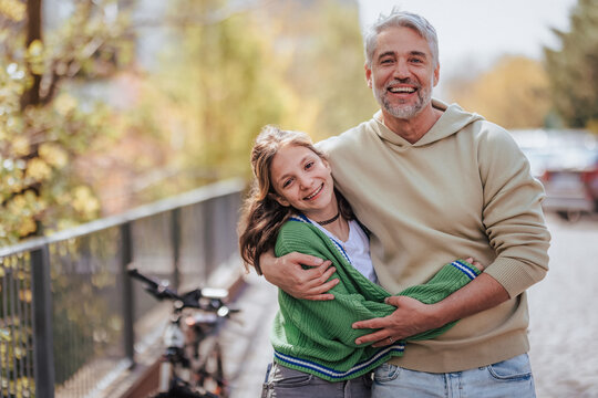 Teenage Daughter Hugging Her Father Outside In Town When Spenidng Time Together.