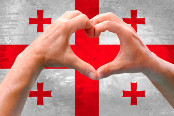 close-up of male hands in heart form against background of silk national flag of European state of...