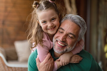 Portrait of little cute daughter hugging her happy father at home.