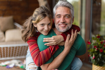 Obraz premium Portrait of teenage daughter hugging her happy father at home.