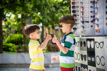 A child and a choice of sunglasses. Two little boys are standing in sun-proof glasses against the...