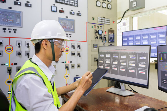 Male Engineerr Working In Electrical Control Room In The Heavy Factory. Professional Industrial Engineer Operating In Electricity Substation.