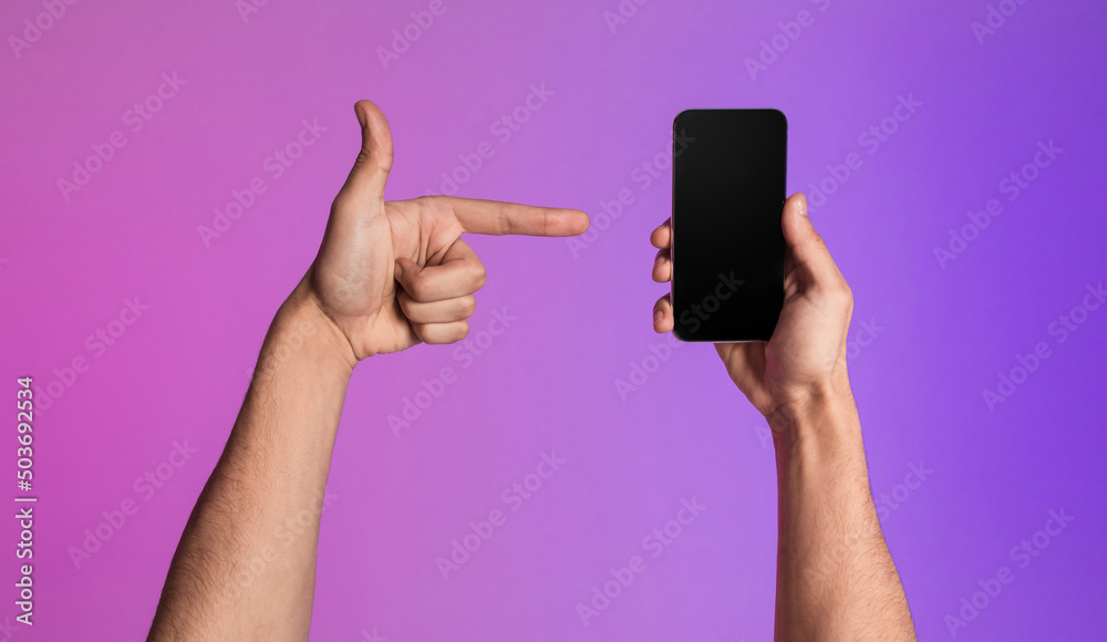 Poster Closeup of young guy pointing at smartphone with empty black screen, showing space for new mobile app or website
