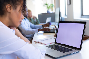 African american mid adult businesswoman using laptop with blank screen while working in office