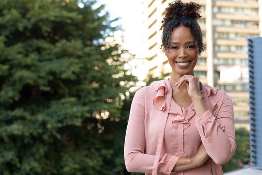 Portrait of smiling african american mid adult businesswoman with hand on chin standing in balcony