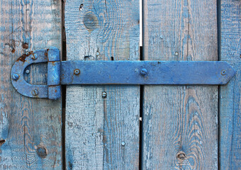 Old metal door hinge close-up on a wooden fence
