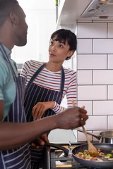 Fotobehang Multiracial young couple cooking food together at home © wavebreak3