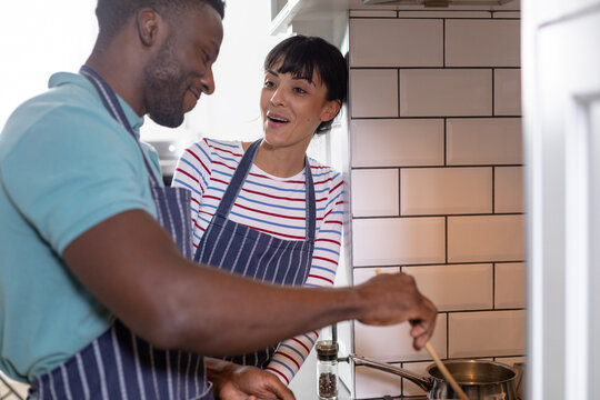 Happy multiracial young couple cooking food together at home