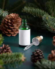 Dropper Bottle near fir branches and pine cones close up. Brand packaging mockup.