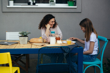 mother and daughter talking while having breakfast in their back yard